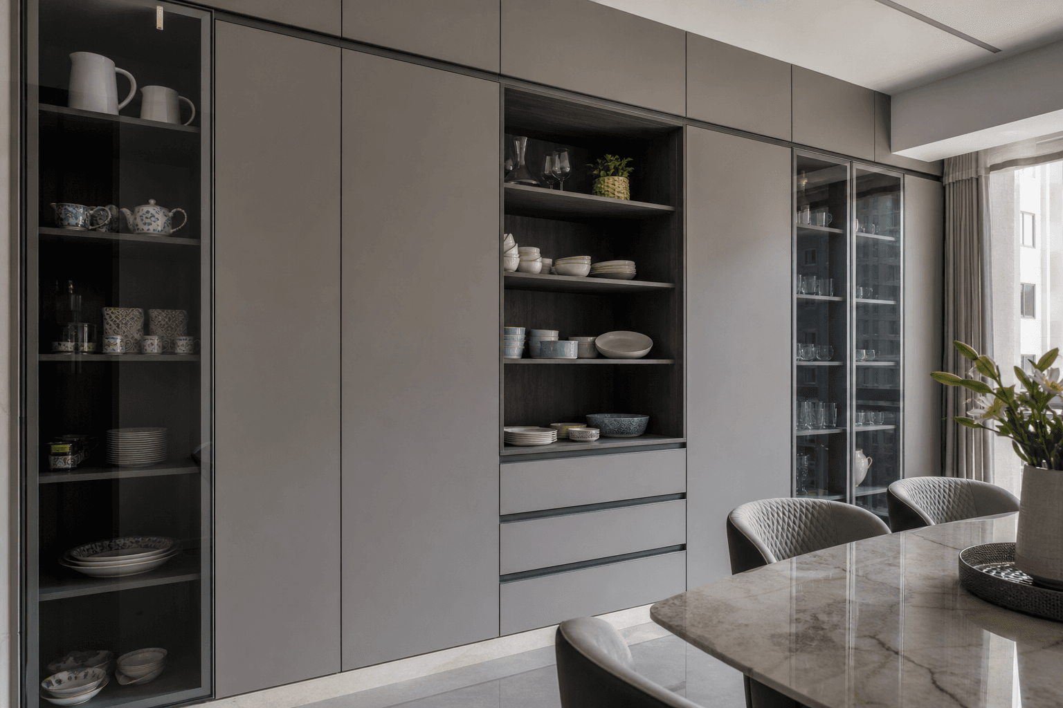Floor-to-ceiling crockery storage with matte grey shutters in a contemporary Indian home