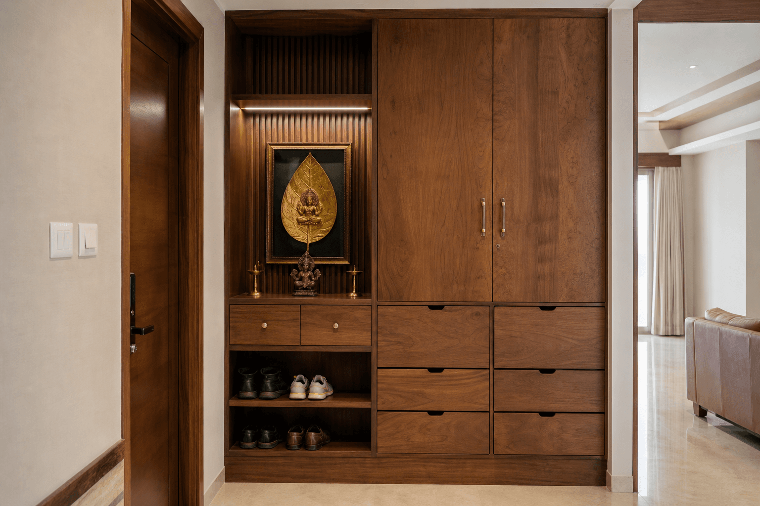 Walnut-finish foyer storage with shoe drawers and display niche in a 3BHK home