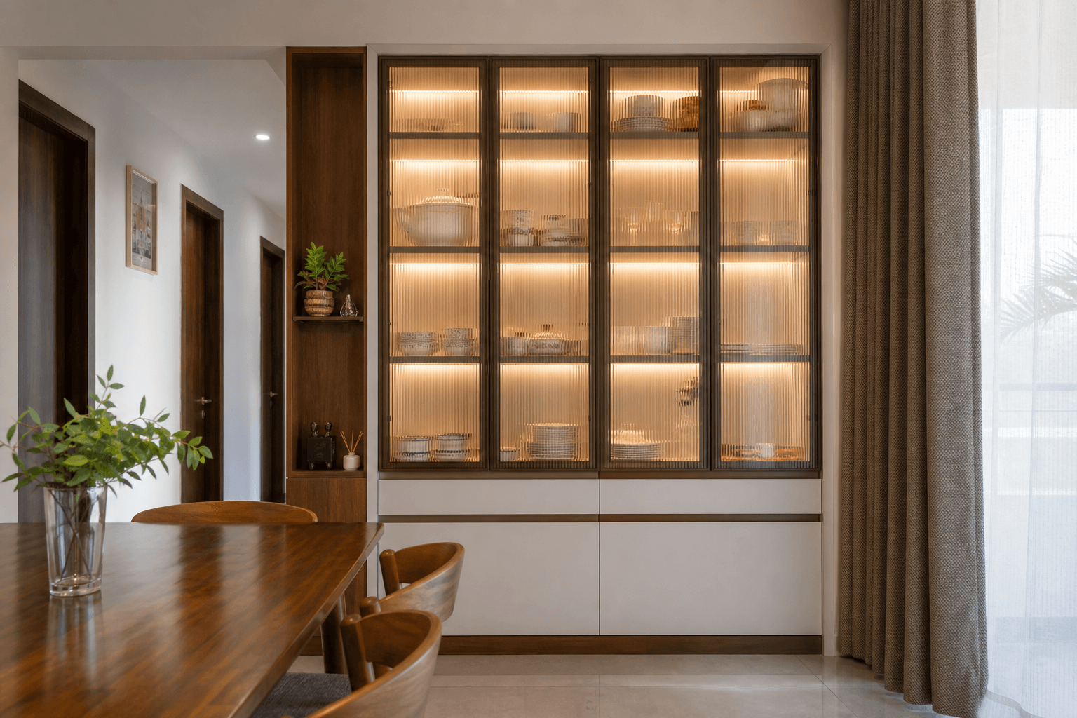 Fluted glass crockery display unit with warm internal lighting in an Indian dining space
