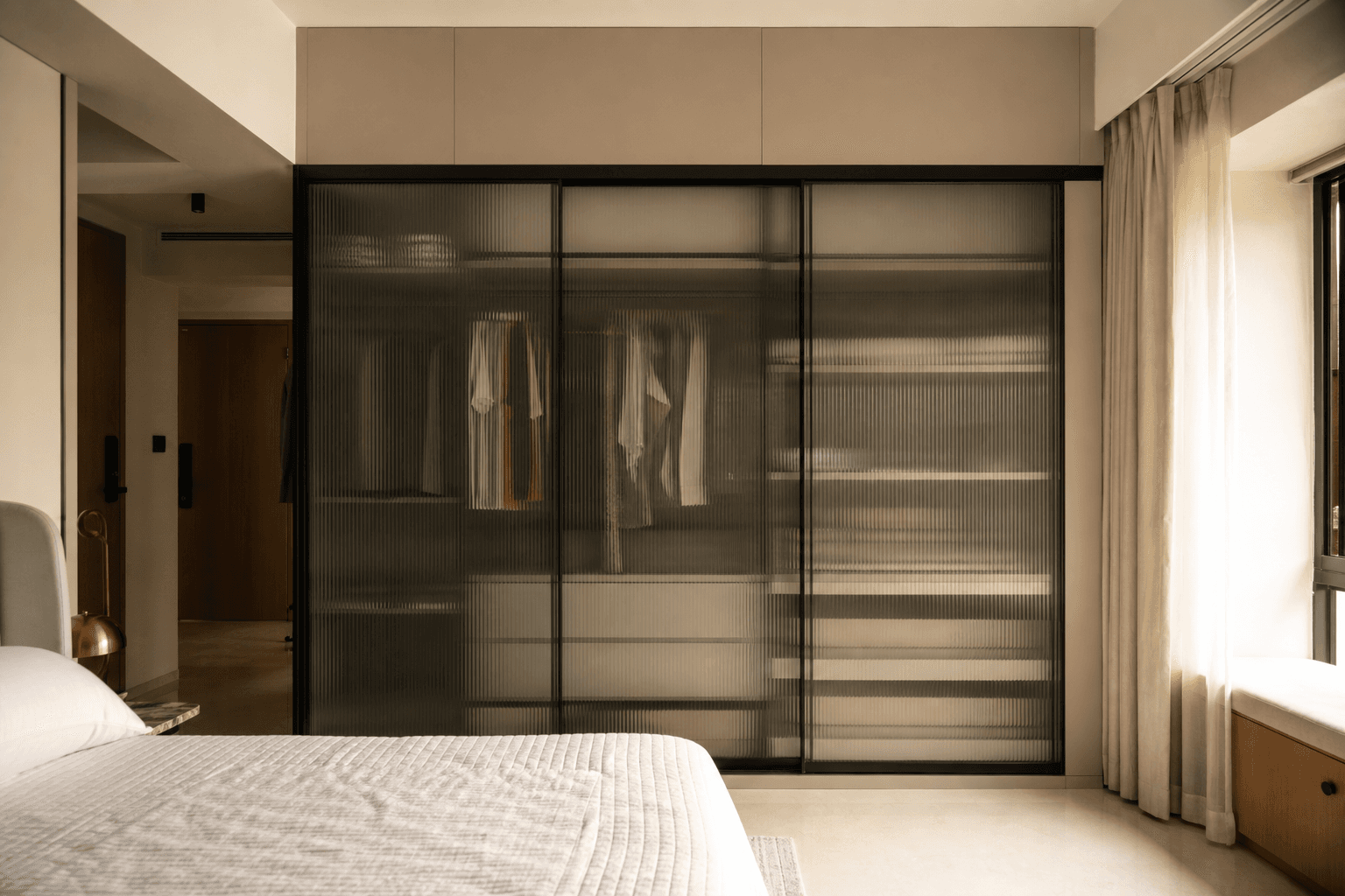Integrated wardrobe wall with fluted glass shutters in a premium Indian bedroom